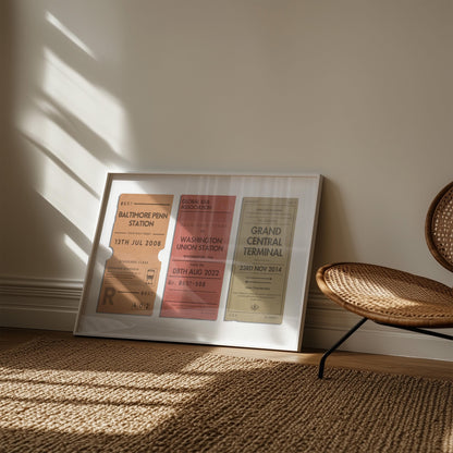 A muted tone of colour art print showing retro railway tags with custom details and destinations on them. The art is leaning on the wall in a boho style living room with a rattan rug and chair.