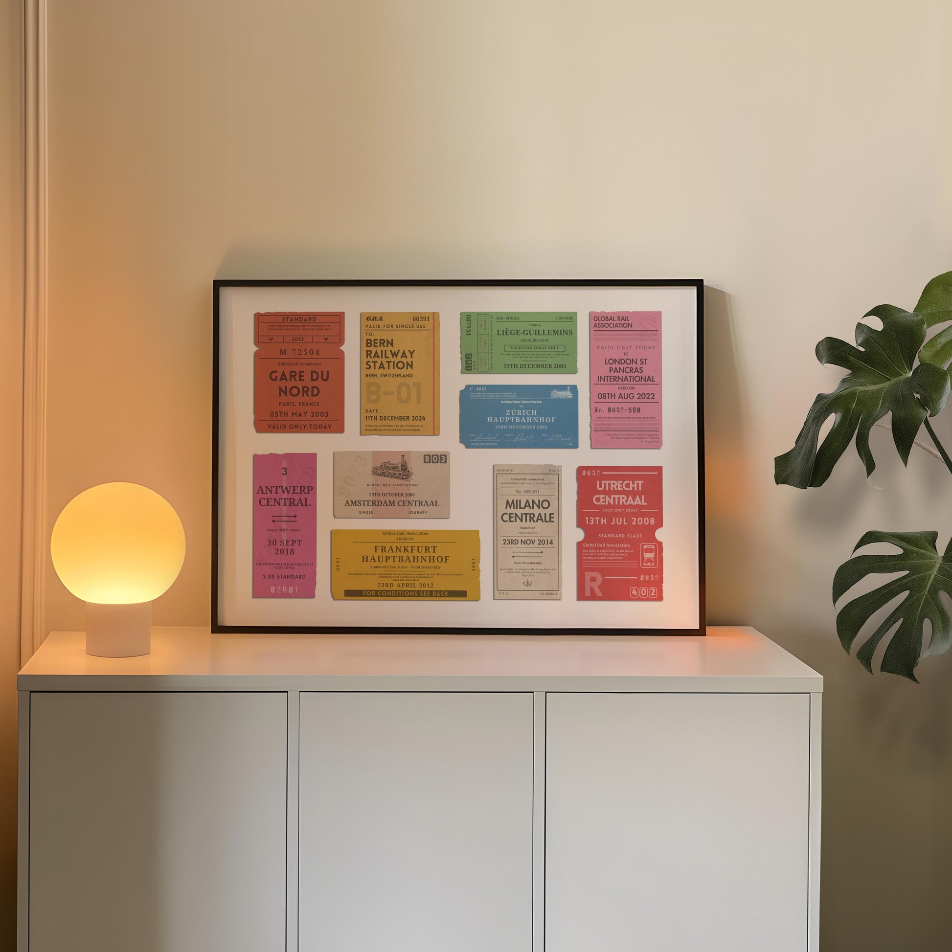 A cosy apartment with a round lamp and plant. A poster i leaning on the wall is a one of a kind railway stubs artwork made for travel lovers as a keepsake for rail journeys and holidays.