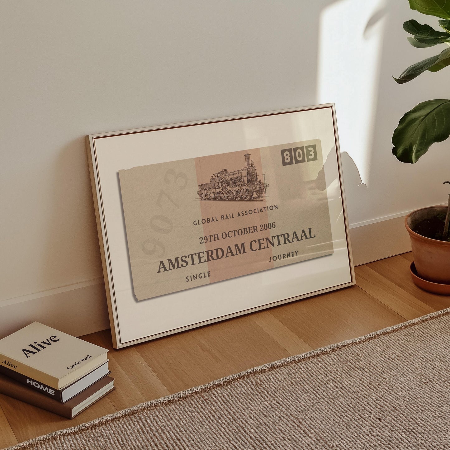 A minimalist apartment hallway with books and a poster on the floor. The print is a travel keepsake with a bespoke vintage rail luggage tag made as a trendy holiday memory décor piece.