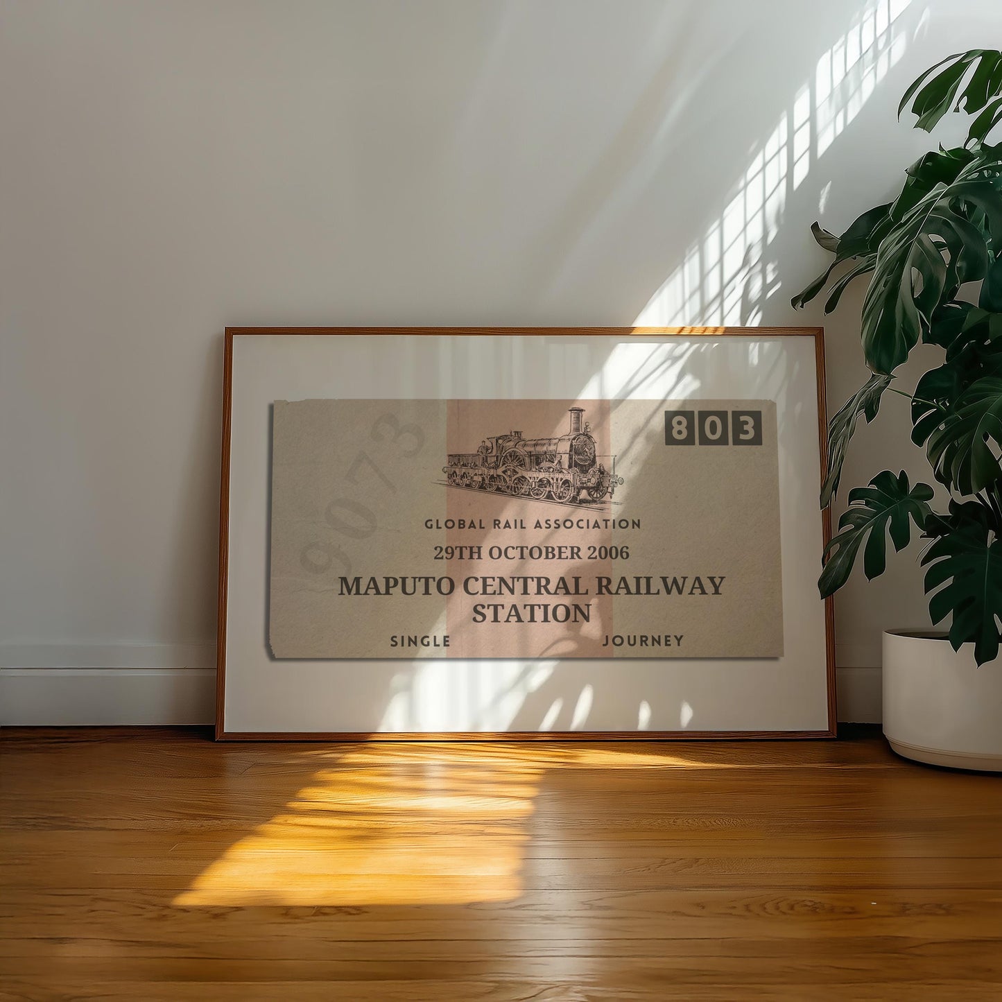 A well lit office space with a large plant and retro colour filled wall art decor. The poster has an old style ticket stub on it for interrail trips and train journeys from your travels. The art has been made bespoke with your destination, date and station.