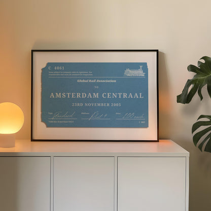 A cosy bedroom with a white sideboard. A poster is on top leaning on the wall which is a one of a kind railway stub artwork made for travel lovers as a keepsake for rail journeys and holidays.