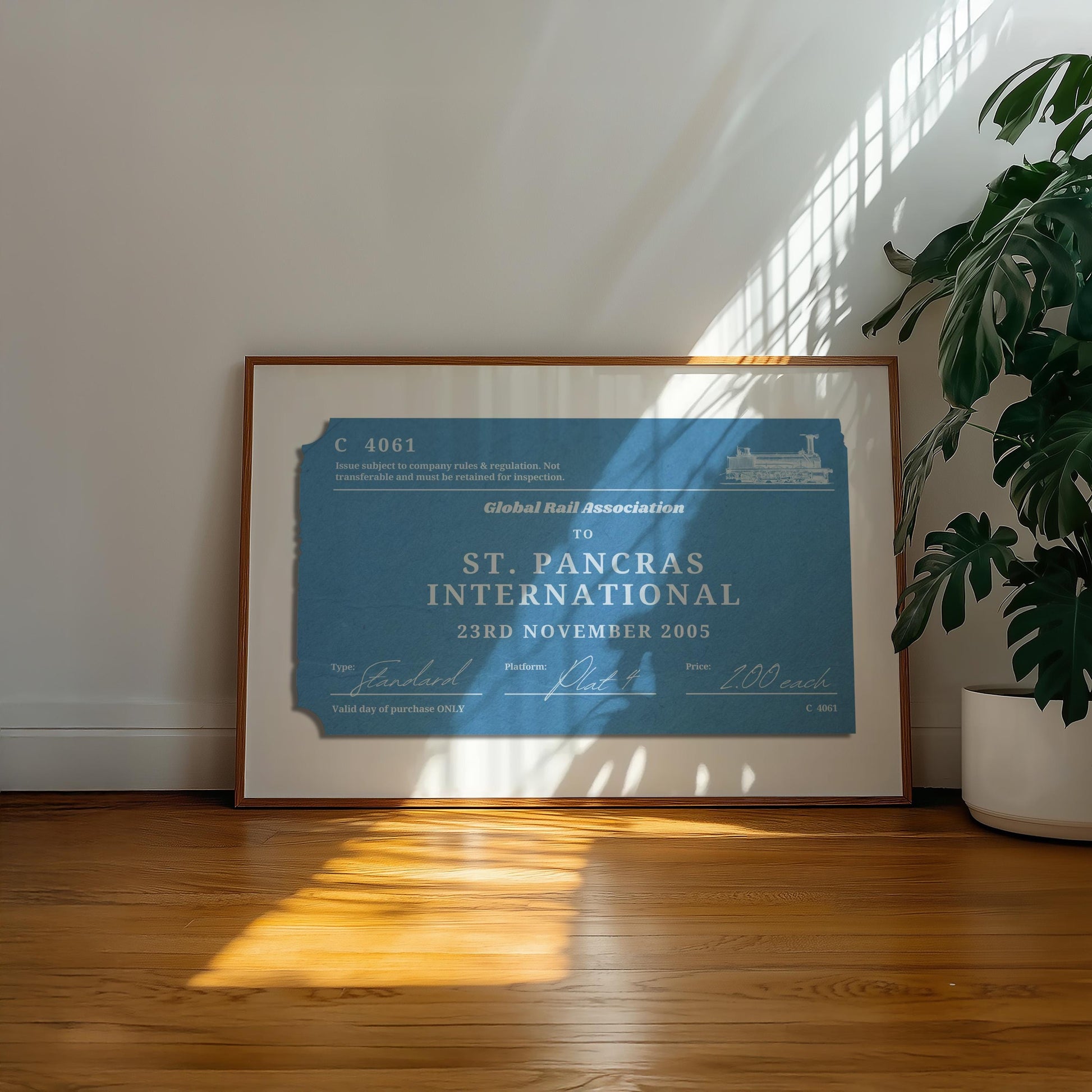 A well lit office space with a large plant and retro colour filled wall art decor. The poster has an old style ticket stub on it for interrail trips and train journeys from your travels. The art has been made bespoke with your destination, date and station.