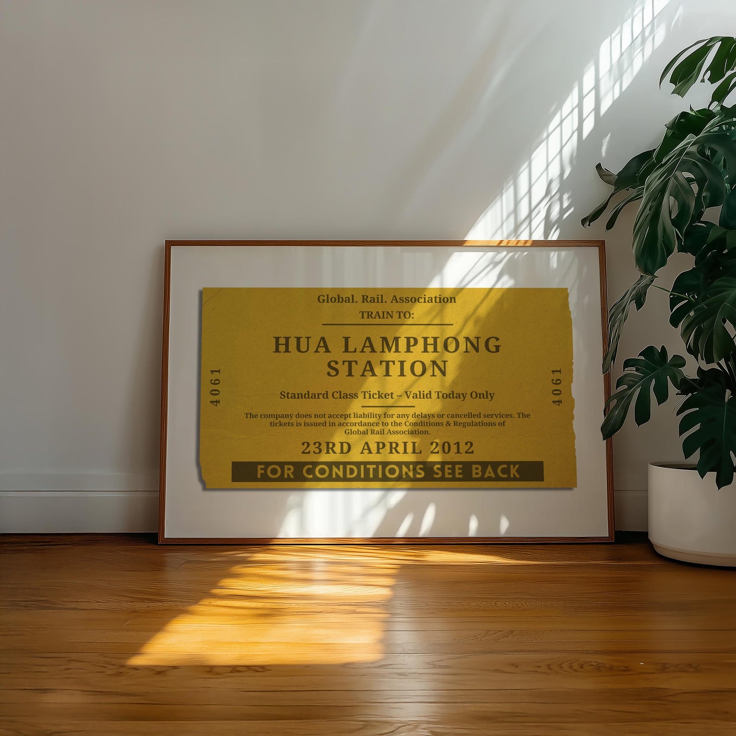 A well lit office space with a large plant and retro colour filled wall art decor. The poster has an old style ticket stub on it for interrail trips and train journeys from your travels. The art has been made bespoke with your destination, date and station.