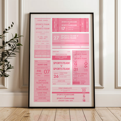 A framed sports event ticket poster print in pink and white, leaning against a white paneled wall on a light wood floor next to a green plant.