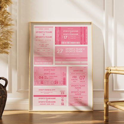 A framed sports ticket print in pink and white tones, leaning against a white wall on a wooden floor next to a bamboo chair.
