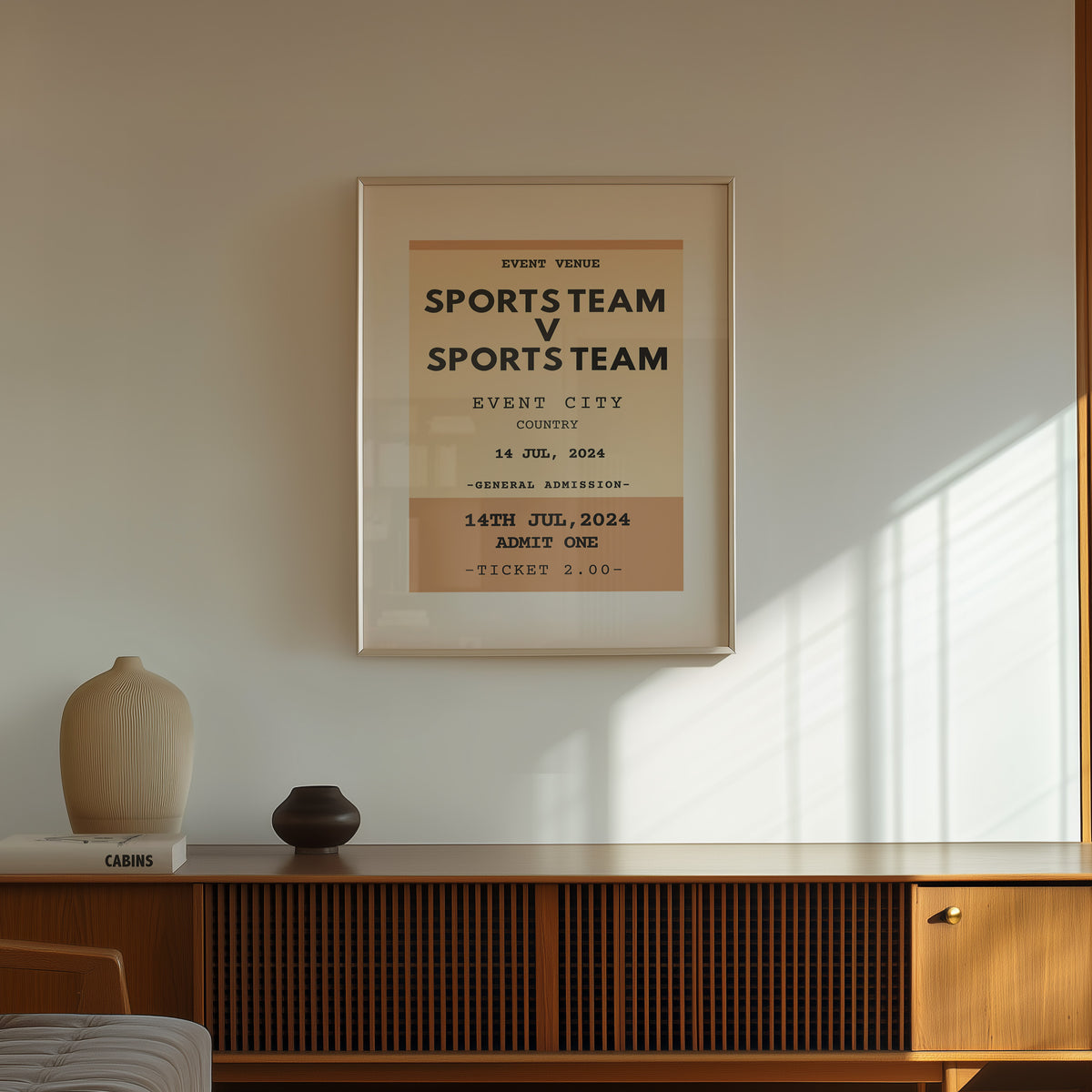 A framed minimalist customisable sports team poster hangs on a beige wall above a wooden console table with decorative vases in a sunlit room.